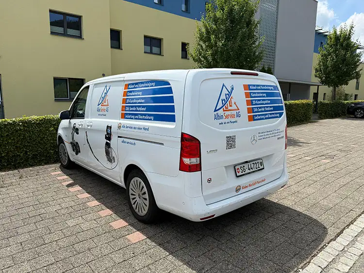 Ein VW-Van mit einem Albin Service Schriftzug steht vor einem Gebäude.